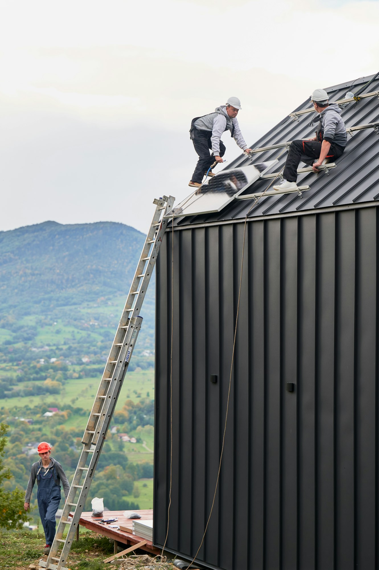 Men workers installing solar panels on roof of house.