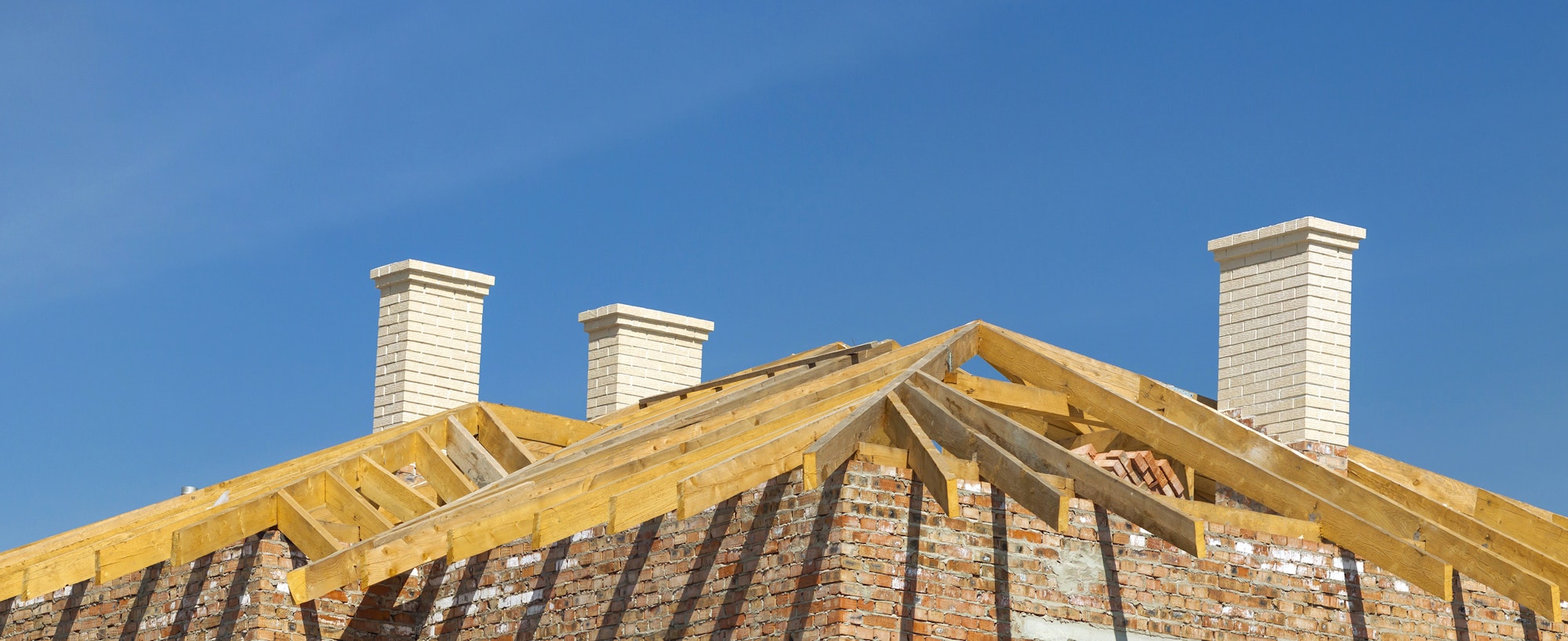 Roofing Construction. Wooden Roof Frame, White Chimneys and Yellow Brick House Construction